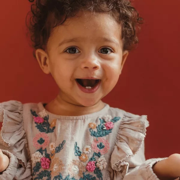 a baby laughing and wearing a dress