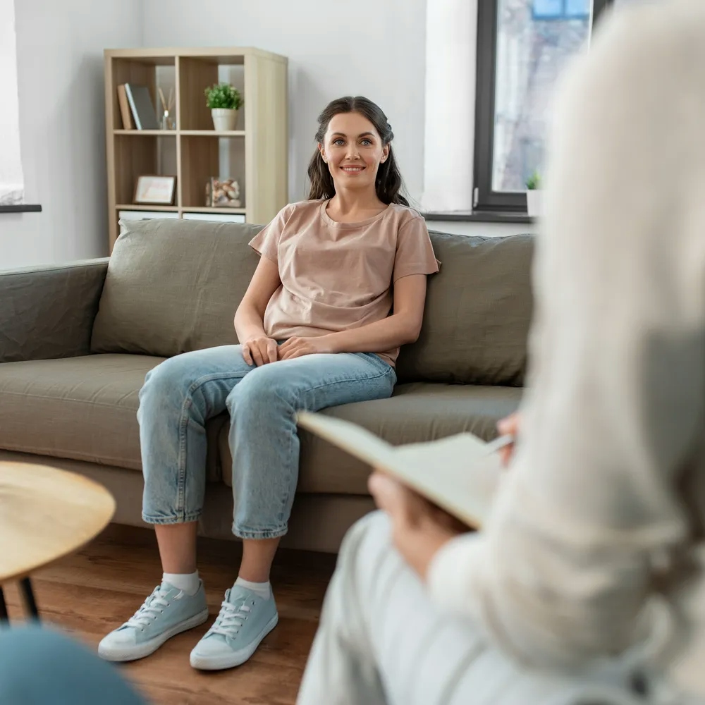 Smiling woman sitting on sofa speaking with a counsellor