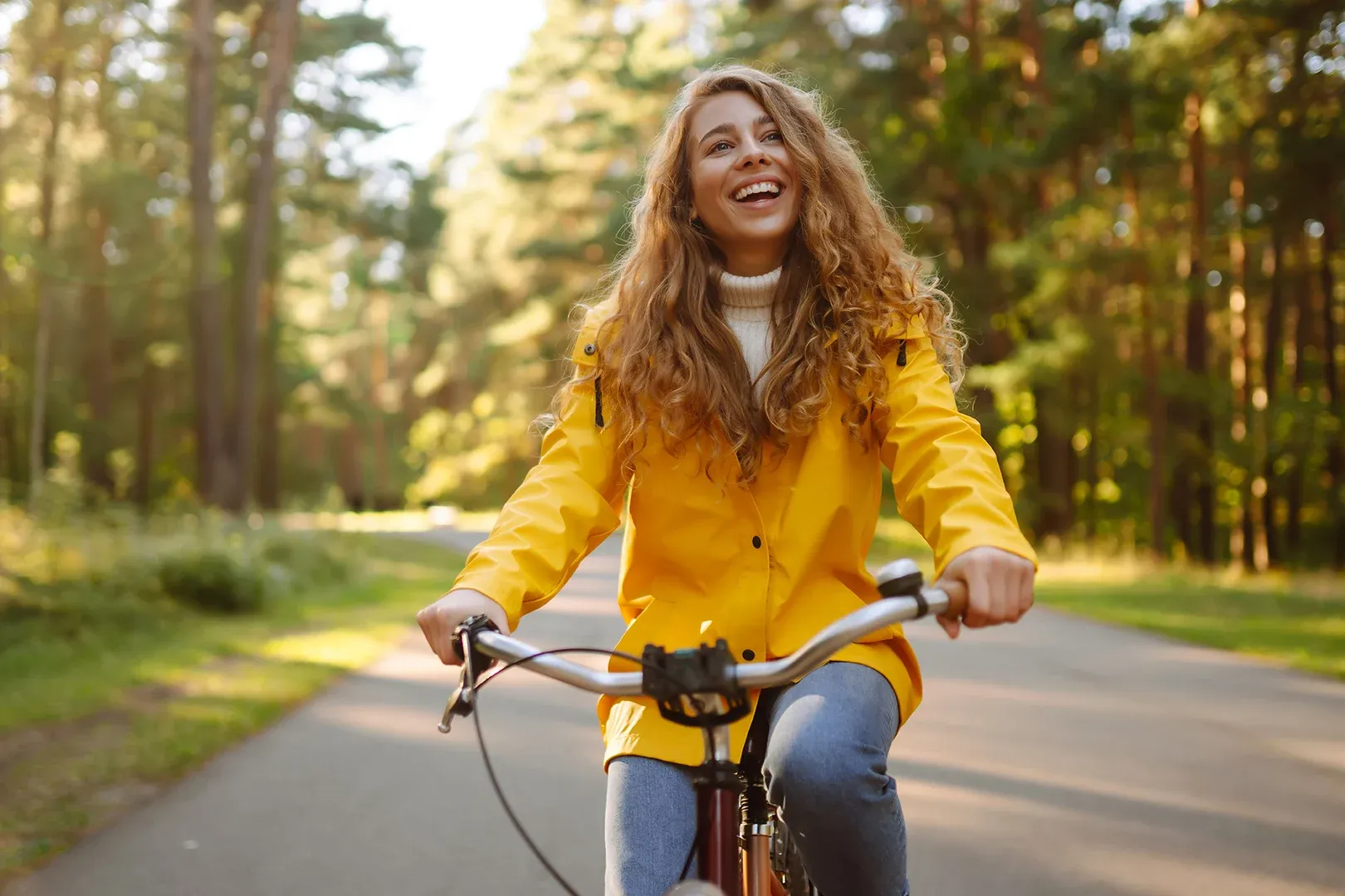 woman smiling and cycling care free on her bike in woodland environment