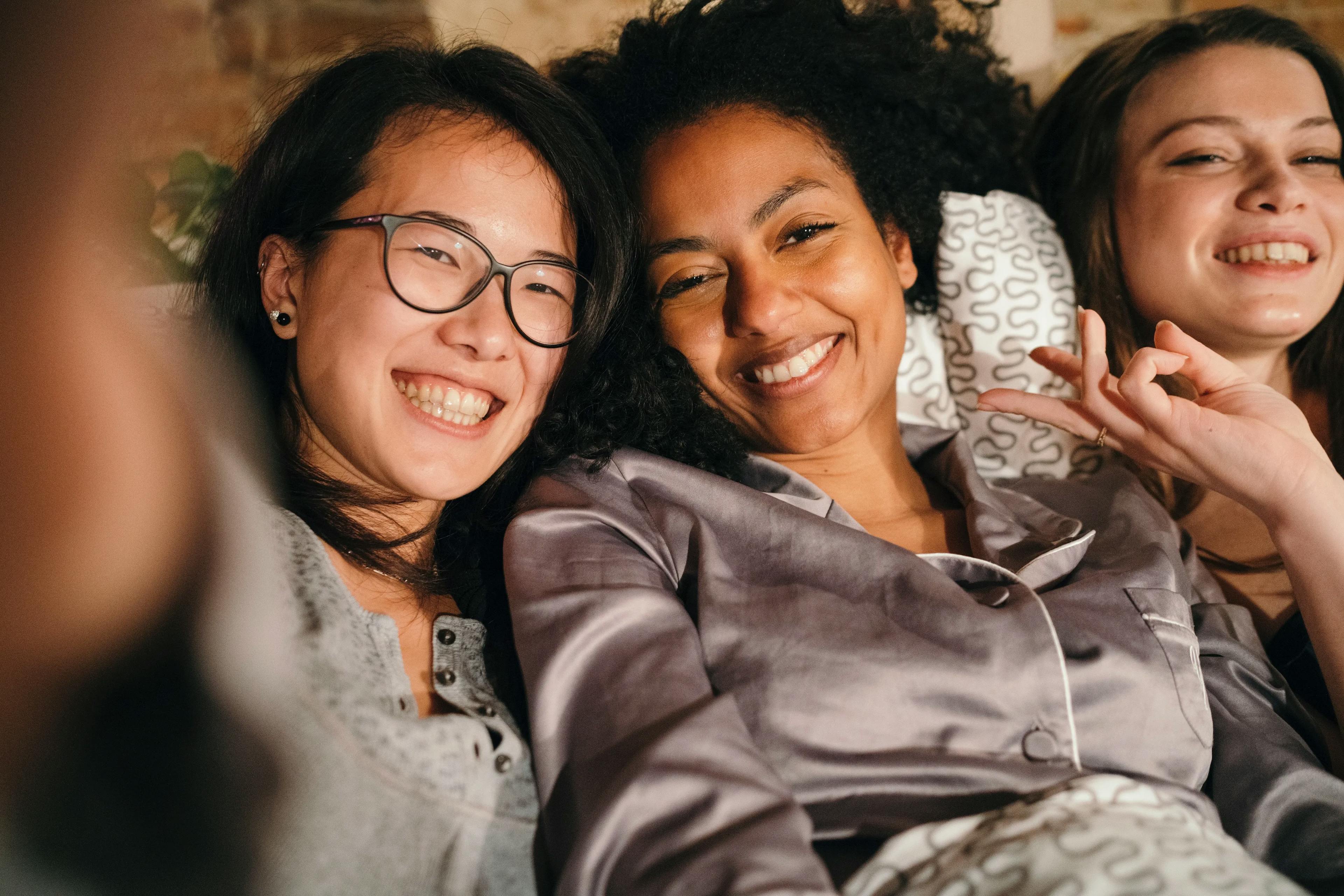 Group of three smiling women on a sofa taking a selfie
