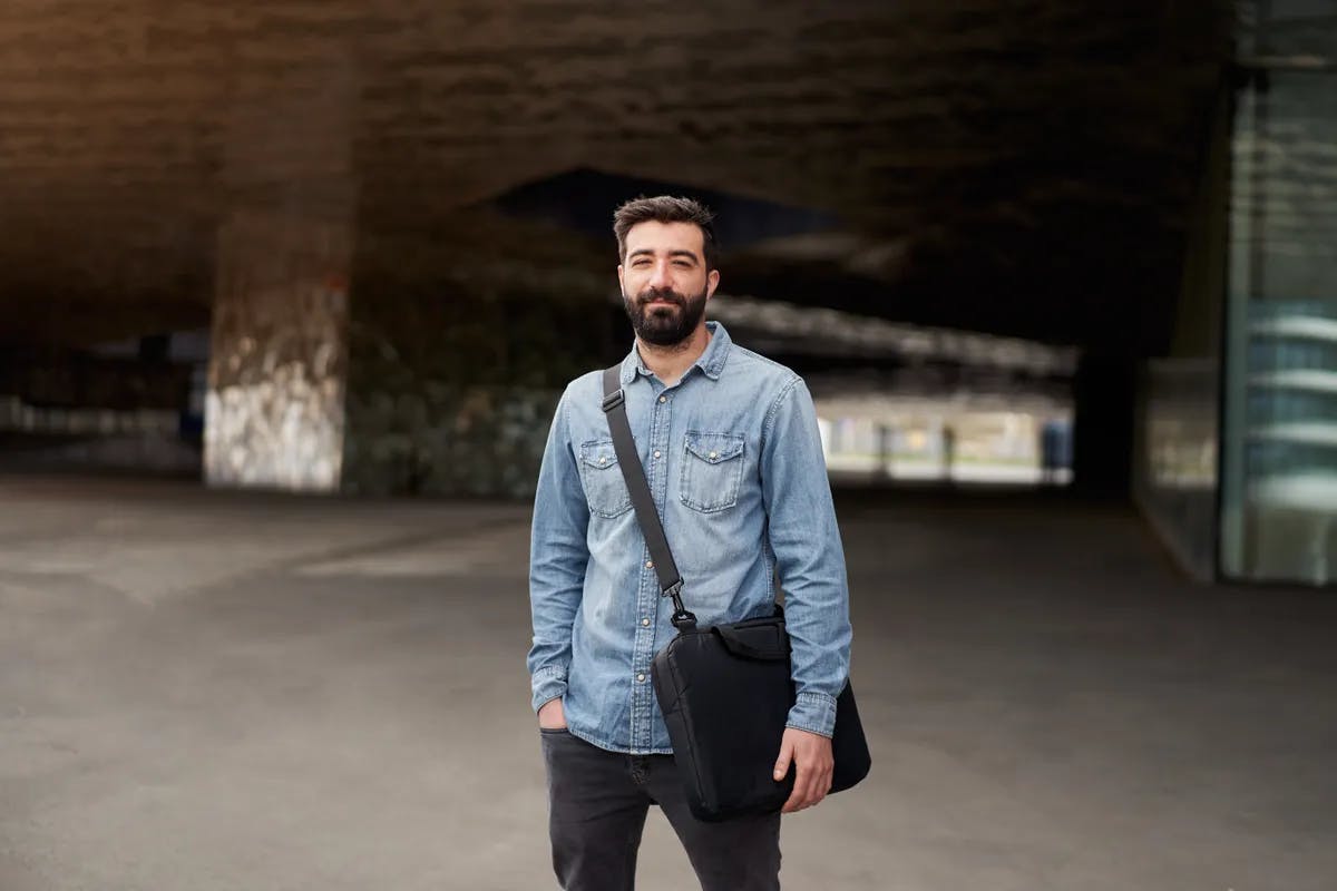 Young man stood in front of a tunnel with a bag