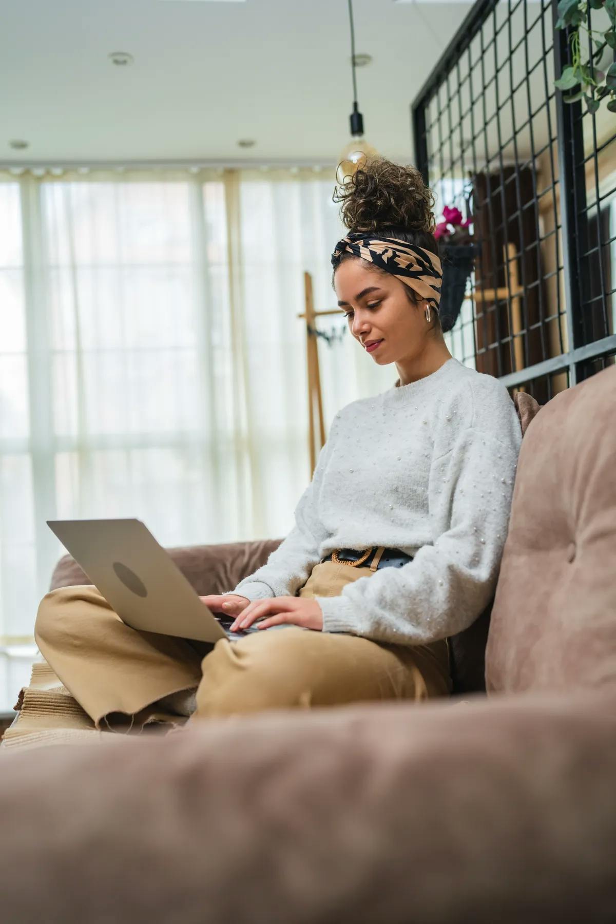 Woman sitting on sofa looking at her laptop that is sitting on her lap