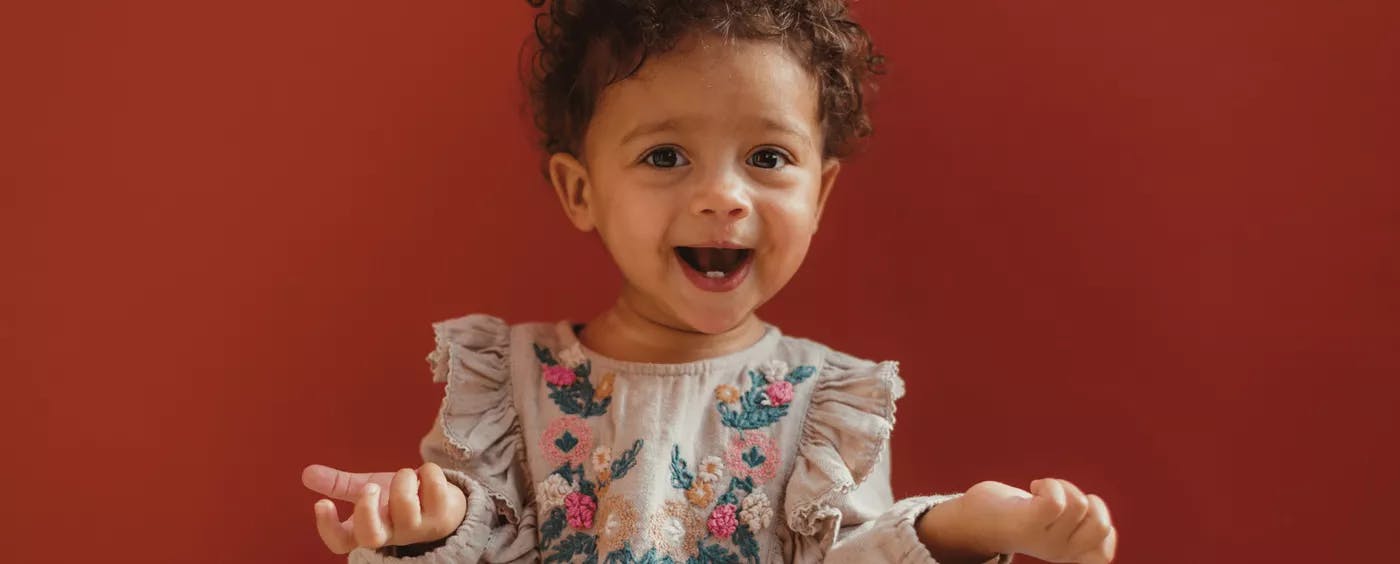 a baby girl in a dress laughing