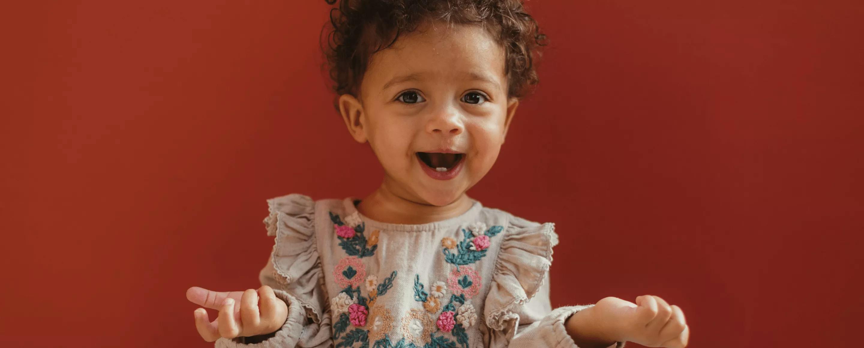 female baby wearing dress and laughing
